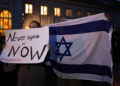 epa10917477 Participants hold an Israeli flag (R) and a placard reading Never again is now (L) in front of the Synagogue at Fraenkelufer in Berlin, Germany, 13 October 2023. As a reaction to the ongoing threat by the militant group Hamas, the German Interior Ministry stated in 'solidarity with Israel', that 'the protection of Jewish and Israeli institutions in Germany was immediately strengthened.'. Activists announced a symbolic protection vigil in front of the Fraenkelufer Synagogue for the evening of 13 October 2023. Thousands of Israelis and Palestinians have died since the militant group Hamas launched an unprecedented attack on Israel from the Gaza Strip on 07 October 2023, leading to Israeli retaliation strikes on the Palestinian enclave. Photo: picture alliance/EPA/CLEMENS BILAN