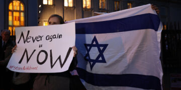 epa10917477 Participants hold an Israeli flag (R) and a placard reading Never again is now (L) in front of the Synagogue at Fraenkelufer in Berlin, Germany, 13 October 2023. As a reaction to the ongoing threat by the militant group Hamas, the German Interior Ministry stated in 'solidarity with Israel', that 'the protection of Jewish and Israeli institutions in Germany was immediately strengthened.'. Activists announced a symbolic protection vigil in front of the Fraenkelufer Synagogue for the evening of 13 October 2023. Thousands of Israelis and Palestinians have died since the militant group Hamas launched an unprecedented attack on Israel from the Gaza Strip on 07 October 2023, leading to Israeli retaliation strikes on the Palestinian enclave. Photo: picture alliance/EPA/CLEMENS BILAN