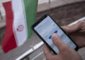 An Iranian park guard enters password on his smartphone as he tries to connect to an Irancell 5G network through the Huawei modem in northern Tehran on February 16, 2021. Irans first 5G network has ran by the Irancell company which is an Iranian telecommunications company that operates Iran's largest 2G-3G-4G-4.5G also 5G mobile network, and fixed wireless TD-LTE internet services. (Photo by Morteza Nikoubazl/NurPhoto via Getty Images)