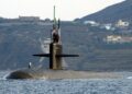 Port bow view showing US Navy (USN) Sailors manning a topside watch aboard the Los Angeles Class Attack Submarine USS NEWPORT NEWS (SSN 750), as the ship departs the harbor at Souda Bay, Crete, Greece following a port visit.